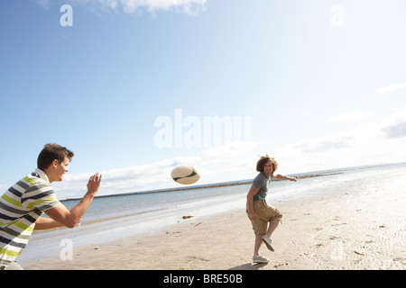 Zwei Jungs im Teenageralter Rugby zu spielen, am Strand zusammen Stockfoto