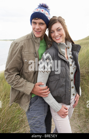 Junge Paare, die durch die Sanddünen, die warme Kleidung zu tragen Stockfoto