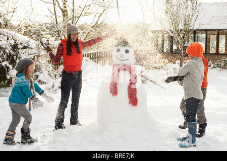 Mutter und Kinder Gebäude Schneemann im Garten Stockfoto