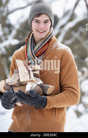 Teenager In verschneiter Landschaft tragen Protokolle Stockfoto