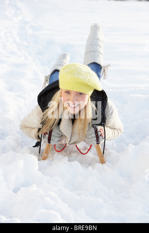 Teenager-Mädchen reiten auf Schlitten In Schneelandschaft Stockfoto