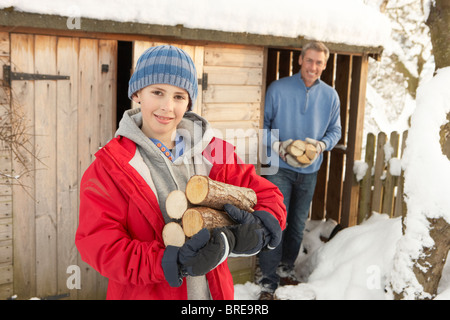 Junges Paar sammeln Protokolle aus Holz laden im Schnee Stockfoto