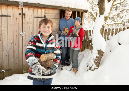 Familie sammeln Protokolle aus Holz laden im Schnee Stockfoto