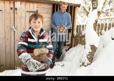 Vater und Sohn sammeln Protokolle aus Holz laden im Schnee Stockfoto