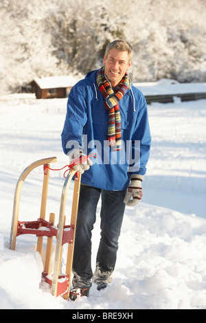 Applying Mann In verschneiter Landschaft mit Schlitten Stockfoto