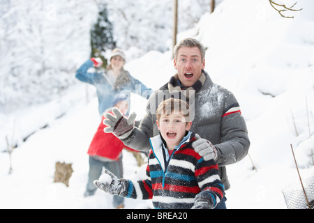 Junge Familie mit Schneeballschlacht In Schneelandschaft Stockfoto
