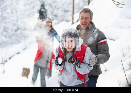 Junge Familie mit Schneeballschlacht In Schneelandschaft Stockfoto