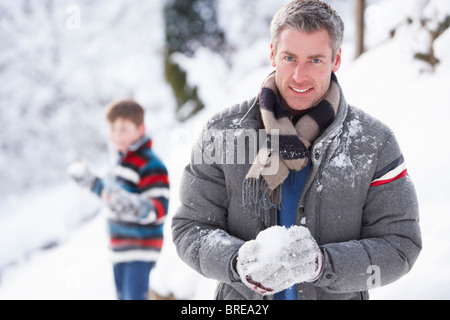 Vater und Sohn mit Schneeballschlacht In Winterlandschaft Stockfoto