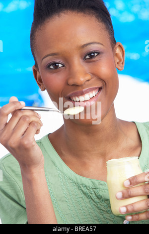 Junge Frau Essen Joghurt im Studio Stockfoto