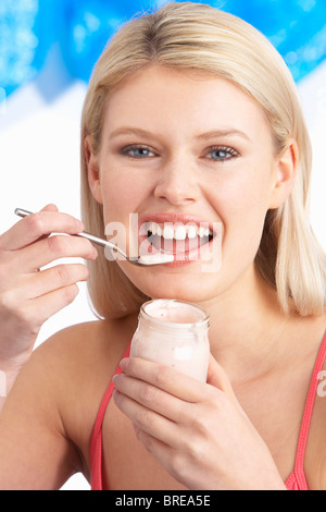 Junge Frau Essen Joghurt im Studio Stockfoto