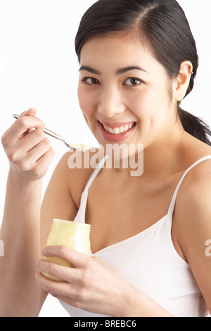 Junge Frau Essen Joghurt im Studio Stockfoto