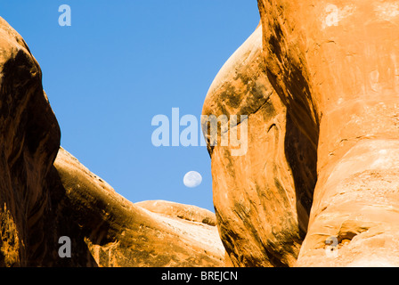 Ein heller Mond geht hinter Sandstein-Formationen im Arches National Park. Stockfoto