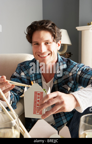Junger Mann entspannte sitzen auf Sofa auf chinesisches Essen zu Hause essen Stockfoto