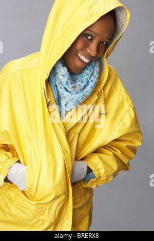 Junge Frau mit gelben Regenmantel im Studio Stockfoto