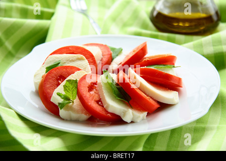 Caprese-Salat auf einem weißen Teller auf grünem Hintergrund Stockfoto