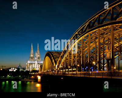 Blick auf Köln mit Eisenbahnbrücke und Dom am Abend. Stockfoto