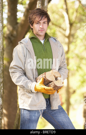 Mann im Freien im Herbst Wald sammeln Protokolle Stockfoto