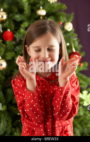 Junges Mädchen Daumen vor Weihnachtsbaum Stockfoto