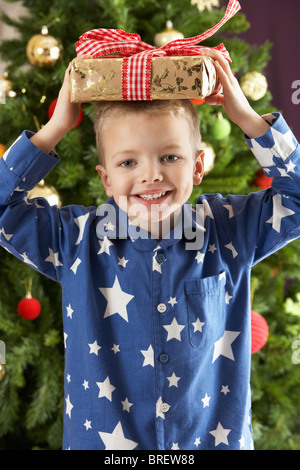 Kleiner Junge hält verpackt Geschenk vor Weihnachten Baum Stockfoto