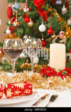 Esstisch mit Christmas Cracker und Dekorationen vor einem Weihnachtsbaum Stockfoto