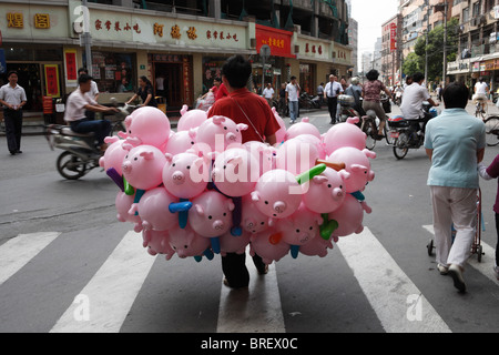 Eine Straße Verkäufer in Shanghai Schwein unter dem Motto Luftballons zu verkaufen. Stockfoto