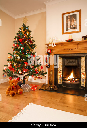 Wohnzimmer mit offenem Kamin, Weihnachtsschmuck und Baum. [Bild über dem Kamin ist Fotografen eigene Arbeit] Stockfoto