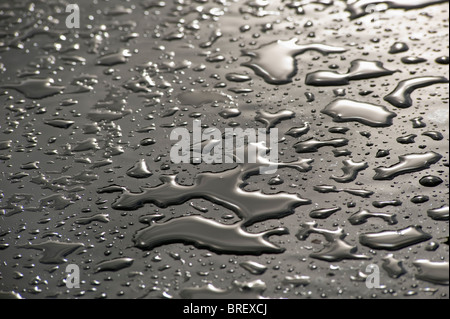 Regentropfen auf einer schwarzen Plexiglas-Oberfläche Stockfoto