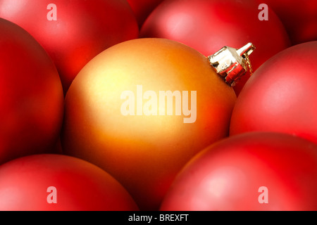 Goldene Weihnachtskugel, umgeben von roten Ornamenten Stockfoto