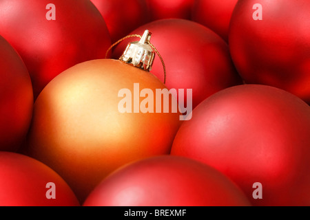 Goldene Weihnachtskugel unter roten Ornamenten Stockfoto