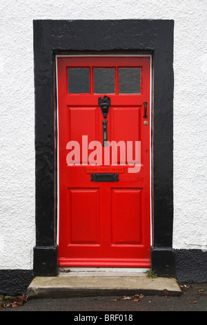 Haustür eines traditionellen britischen Haus leuchtendes Rot lackiert und mit einem Schild Home Sweet Home Stockfoto