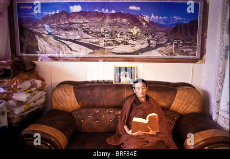 Tibetischen buddhistischen Mönch Dongyu, lesen die Lehren des Buddha in seinem kleinen, aber gut ausgestattet und möblierten Wohnraum bestehend aus Stockfoto