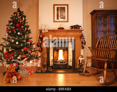Wohnzimmer mit offenem Kamin, Weihnachtsschmuck und Baum. [Bild über dem Kamin ist Fotografen eigene Arbeit] Stockfoto