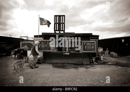 ein Mann und seine Hunde gehen, Fisch vom Fishermans Shop, Hastings, East Sussex, April 2010 Stockfoto