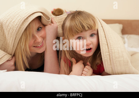 Zwei Schwestern unter Bettwäsche zusammen zu spielen. Stockfoto