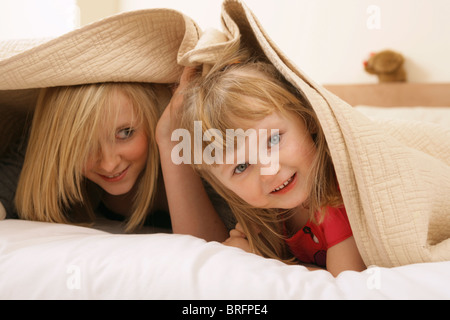 Zwei Schwestern unter Bettwäsche zusammen zu spielen. Stockfoto