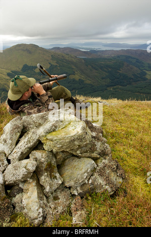 Schottische Hirsch Stalker auf einem Berg, Spionage für Hirsche mit drei zeichnen Teleskop Stockfoto