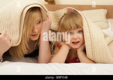 Zwei Schwestern unter Bettwäsche zusammen zu spielen. Stockfoto