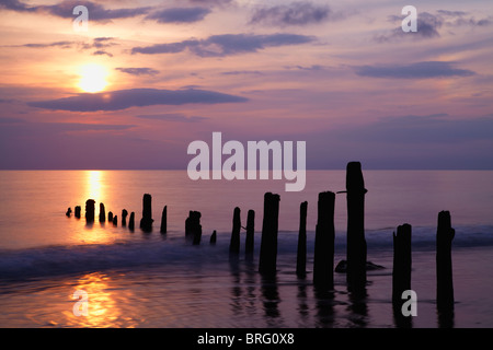 Ein strahlend bunten Himmel leuchtet Whitbys Strand mit Wellen rund um die Buhnen Stockfoto