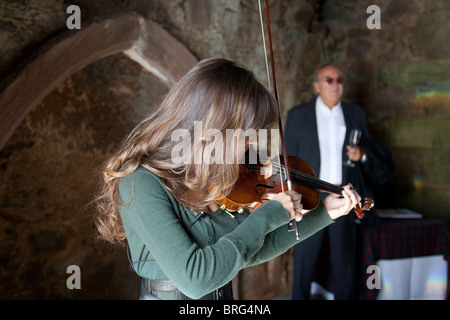 Nicola Benedetti spielen Ihre Stradivari Violine bei der Eröffnung der Portencross Schloss nach der Restaurierung. Ihr Vater Gio ist im Hintergrund. Stockfoto