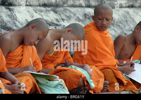 Novizen studieren an der Basis eines großen Stupa am historischen Wat Hua Kuang in Nan, Thailand. Stockfoto