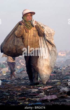 Ein Arbeiter bei der Stung Meanchey Mülldeponie in Phnom Penh, Kambodscha, trägt Säcke Müll auf der Deponie. Stockfoto