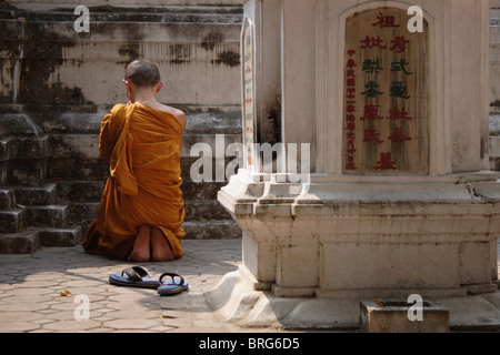 Ein buddhistischer Mönch kniet im Gebet an der Basis eines Stupa in Wat Tor Khar Rnam-Tempel in Chiang Mai, Thailand. Stockfoto