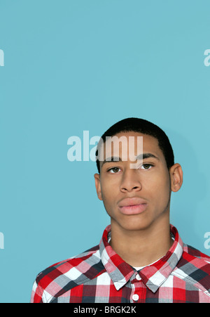 ein zwanziger afroamerikanische Mann steht vor einem hellen blauen Hintergrund mit allerlei Exemplar Stockfoto