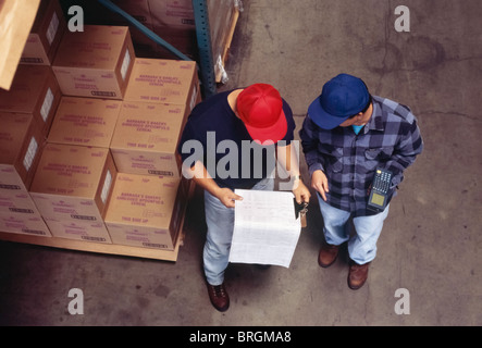 Zwei Arbeiter überprüfen Inventar Blätter im Lager Stockfoto