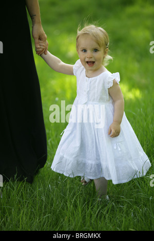 Mutter und Tochter durch üppigen Rasen Hand in Hand gehen. Stockfoto
