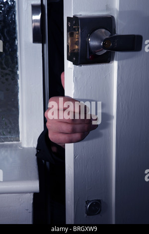 Männliche Hand erscheinen durch eine leicht geöffnete Tür in der Nacht Stockfoto
