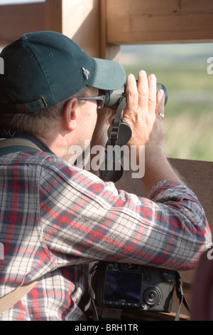 Vogelbeobachter mit dem Fernglas aus innerhalb einer ausblenden oder Blind zu sehen. Stockfoto