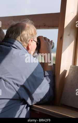 Vogelbeobachter aus in ein Versteck mit dem Fernglas betrachten. Stockfoto