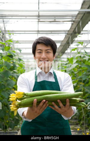 Junger Mann mit Gurken in moderner Bauernhof Stockfoto