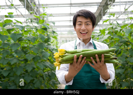 Junger Mann mit Gurken in moderner Bauernhof Stockfoto